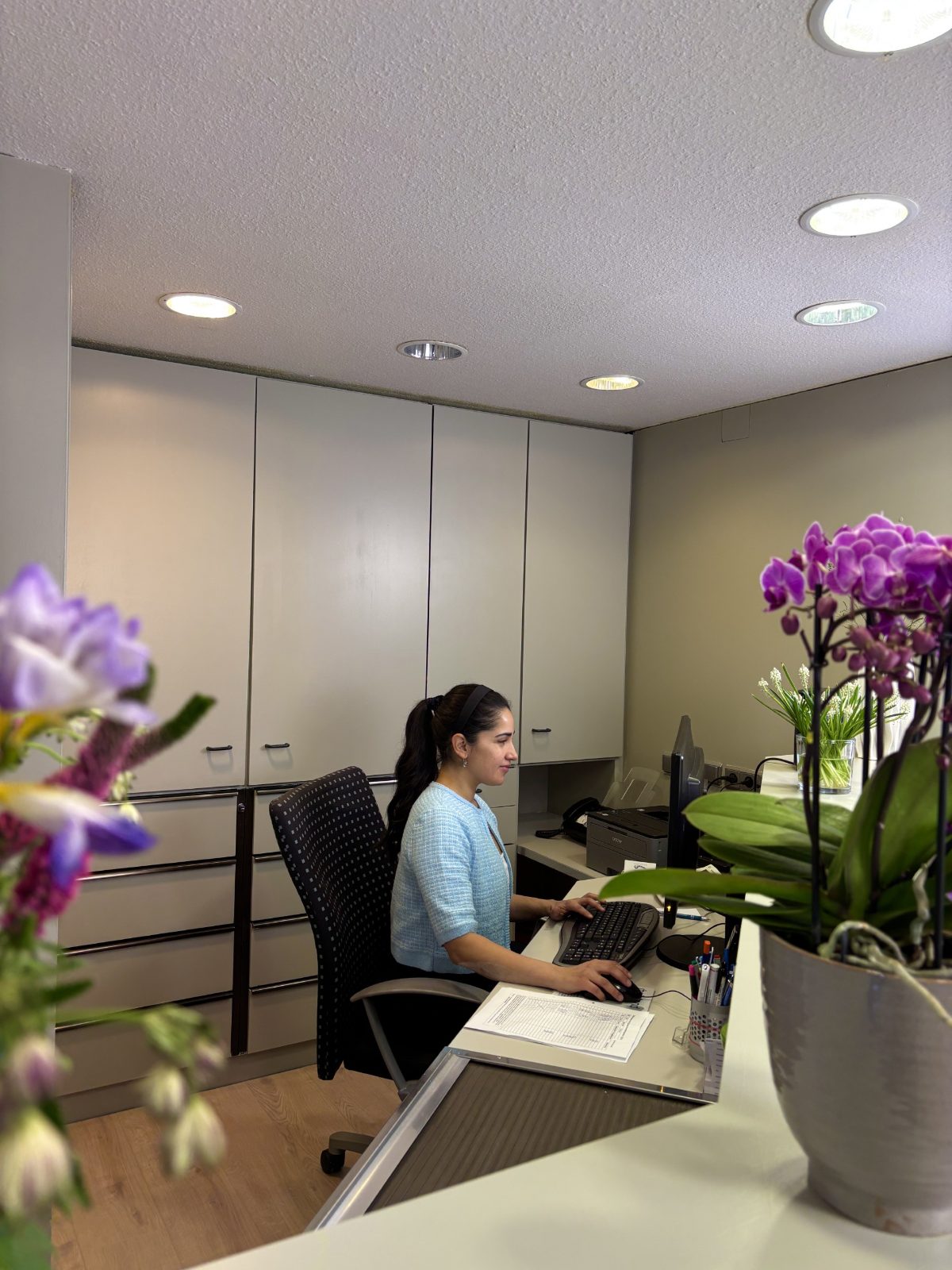 Empfang der Praxis A+ Dental mit Mitarbeiterin und frischen Blumen